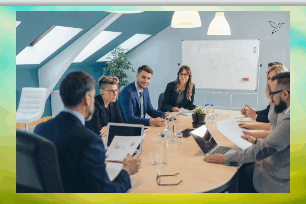 Dieses Bild zeigt einen Meetingraum mit unterschiedlichen Menschen mit Laptop und Papier